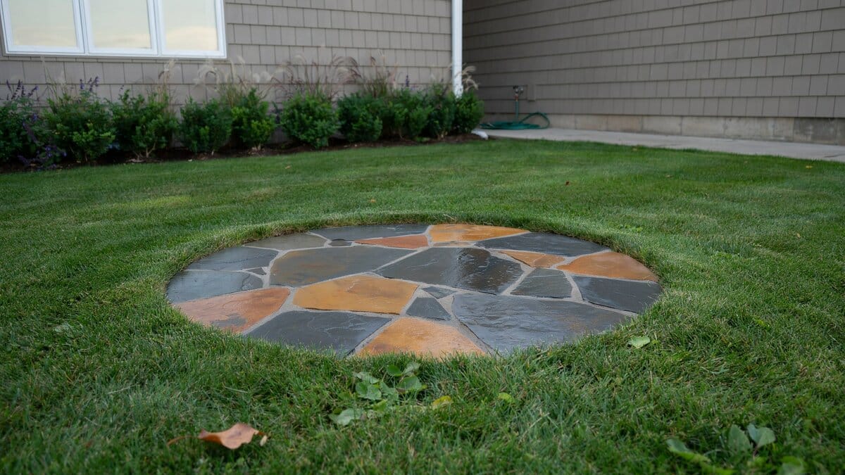 Circle of cut slate set flush into a mown backyard lawn