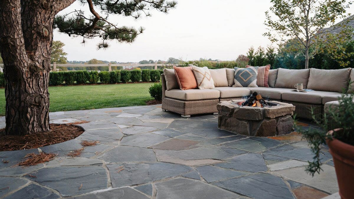 Slate flagstone laid around a pine trunk with rattan sectional and fire pit