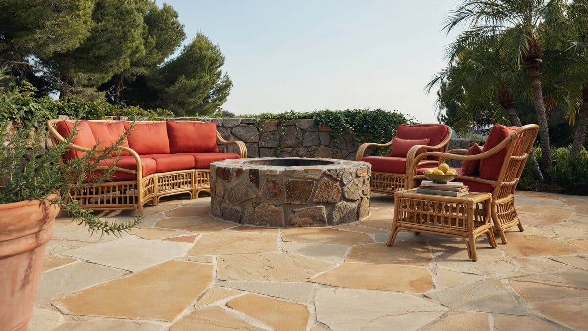 Red cushioned rattan seating circling a rubble stone fire pit on sandstone