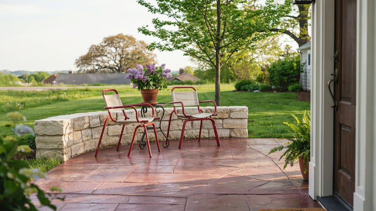 Red metal chairs on maroon flagstone behind a low limestone garden wall
