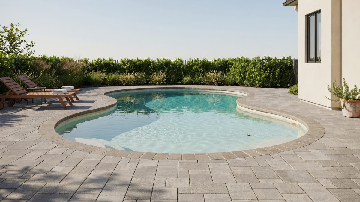 Kidney pool with scalloped edge set into a wide gray paver deck
