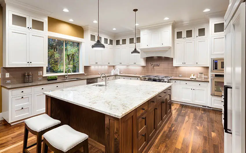 Kitchen with white granite countertop island gray quartz countertops white cabinets wood flooring