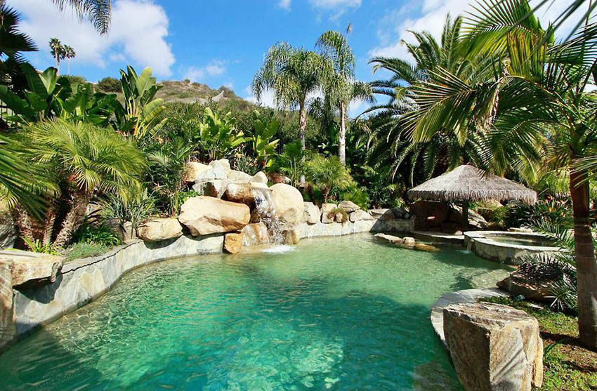 Lagoon swimming pool design with rock waterfall and tropical landscaping