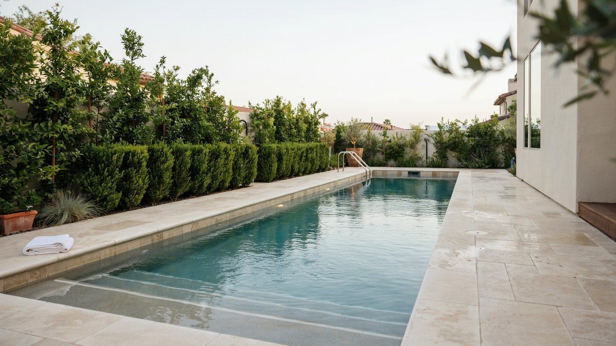 Narrow lap pool bordered by clipped hedges and pale limestone coping