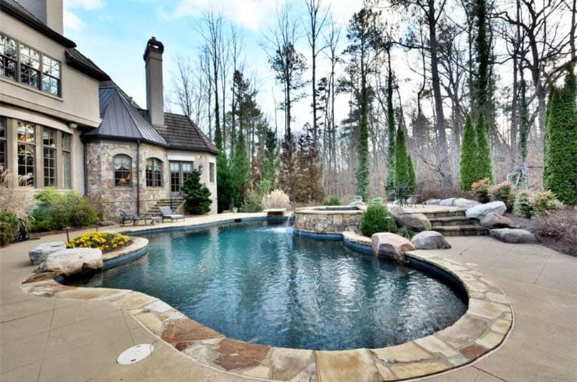 Mountain pond swimming pool design with rock border and spa