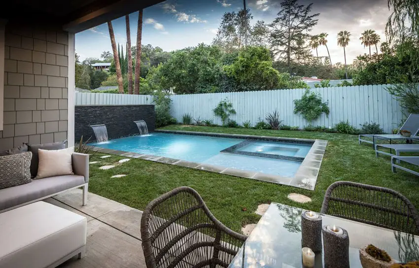 Rectangular pool and spa with stone accent wall and waterfalls
