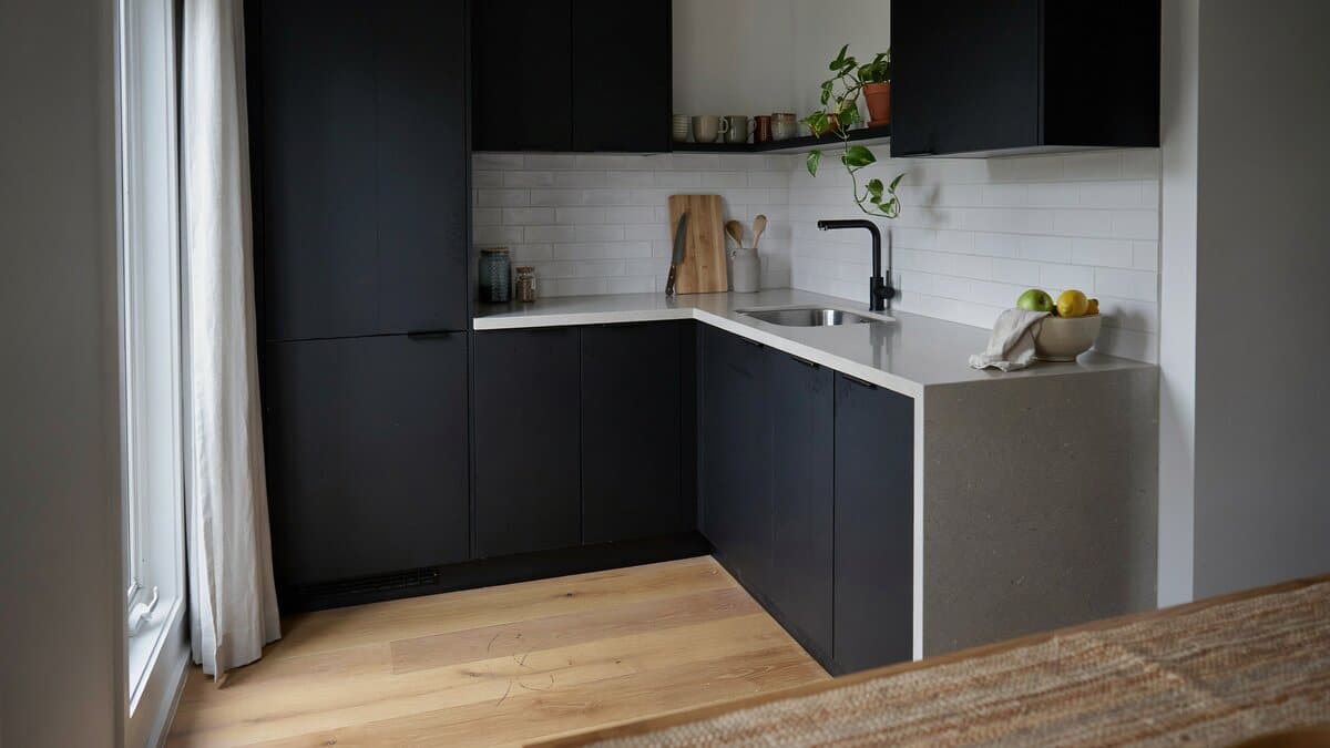 Matte black cabinets turn a short return in this small J shaped kitchen