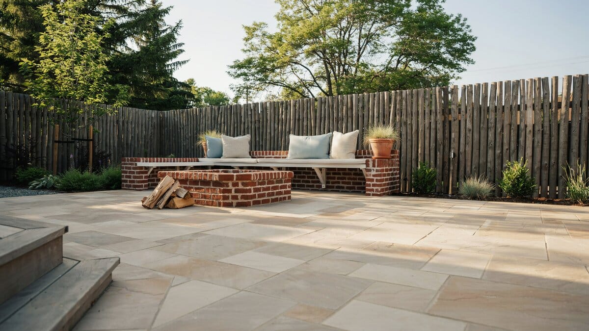 Brick bench and firewood store along a pale sandstone tile patio
