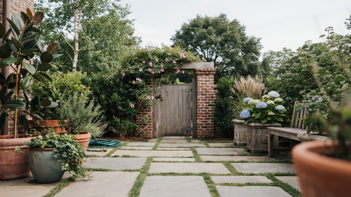 Square pavers with grass joints leading to a wooden garden gate