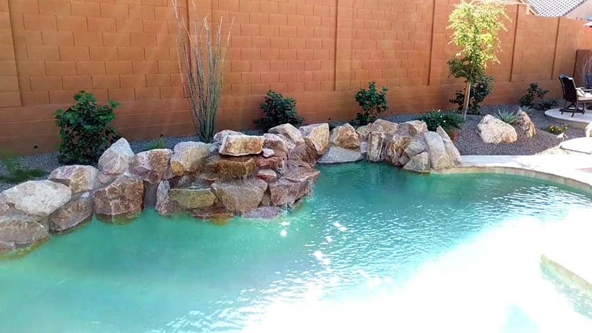Swimming pool with stacked rock waterfall