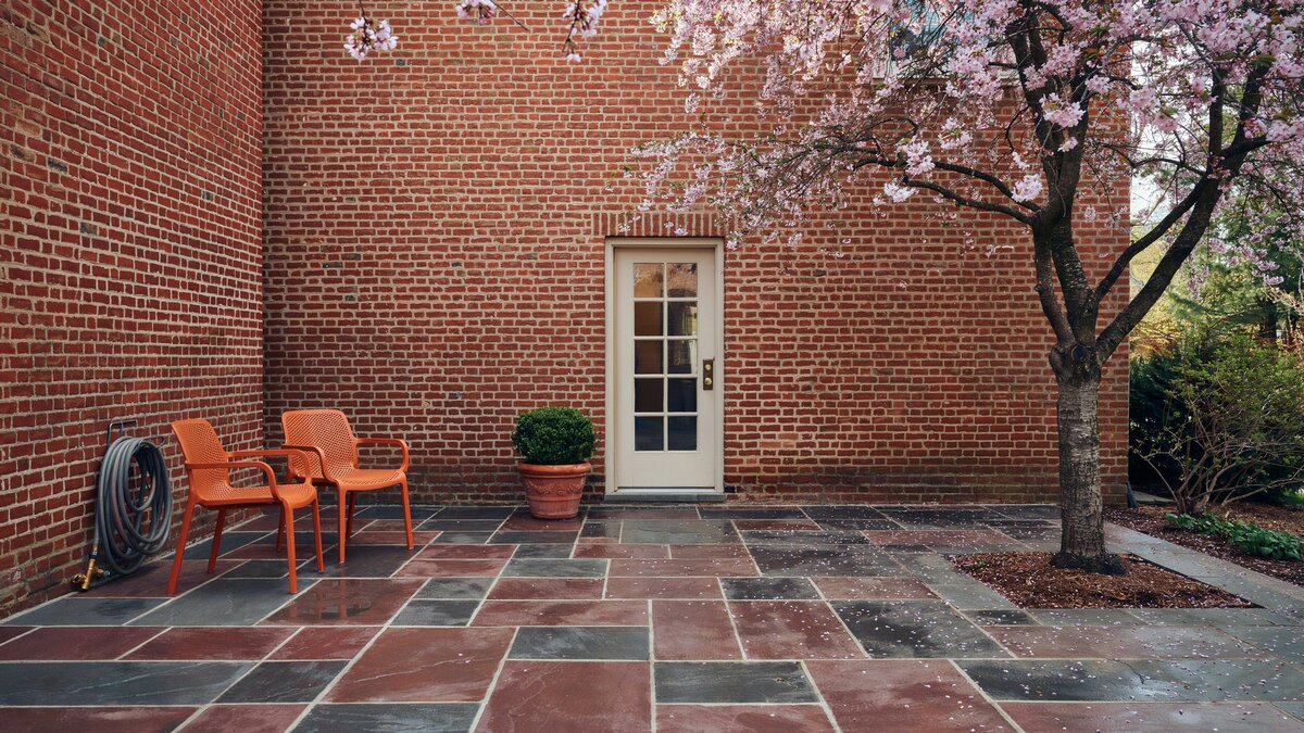 Orange chairs on red and grey slate against a red brick wall