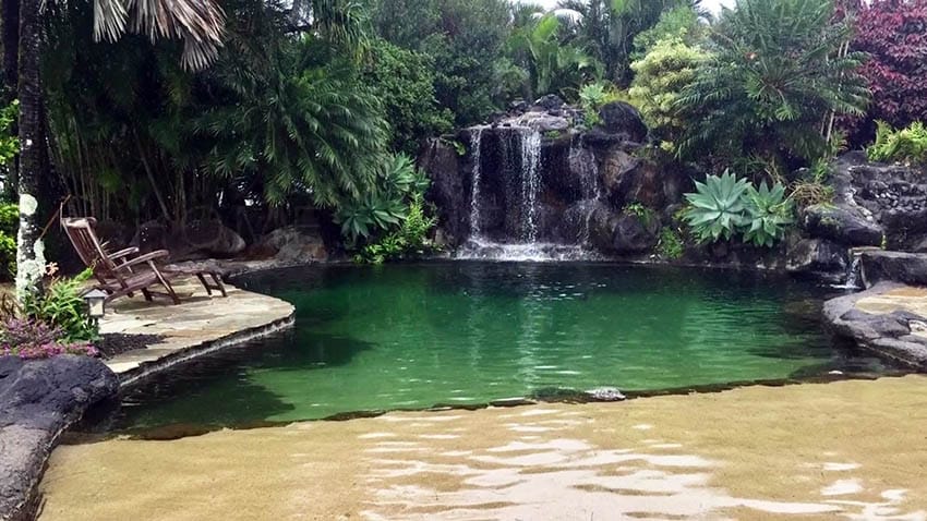 Tropical lagoon pool with large rock waterfall and sand entry