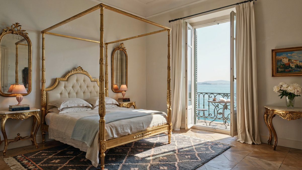 Gold four poster bed with gilt mirrors and balcony doors to a sea view
