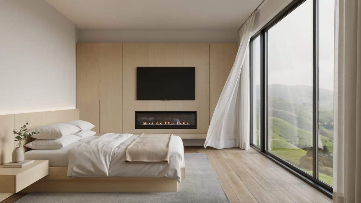 Slim linear fireplace under a wall mounted TV facing rolling green hills