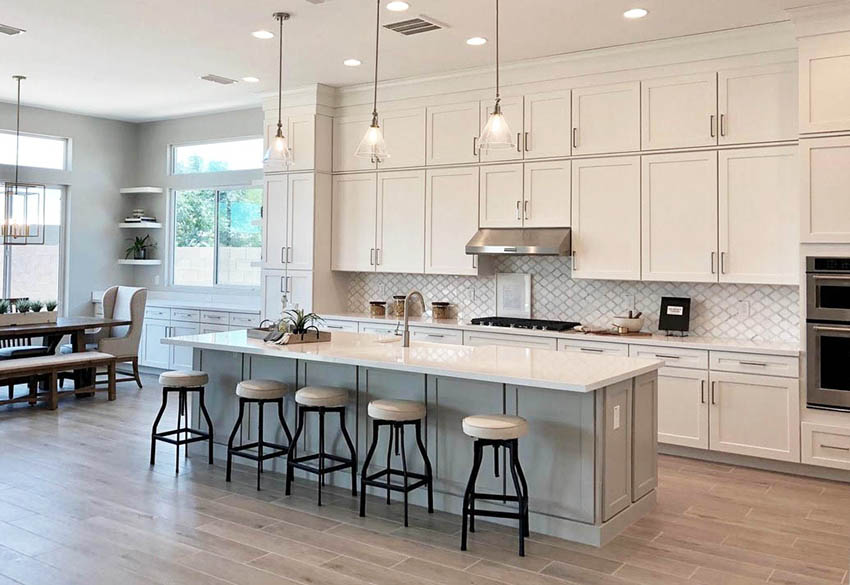 Contemporary kitchen with white cabinets gray island white quartz countertops wood look tile flooring