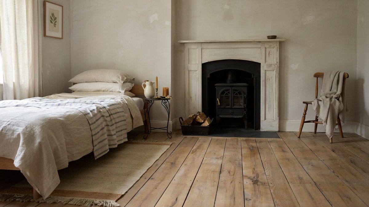 Cast iron stove inside a white paneled surround on wide plank knotty floors