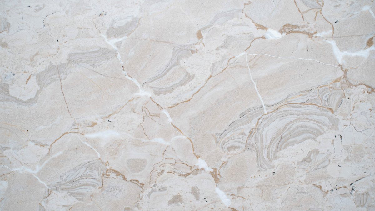 Soft cream surface with gray and tan ripples flowing in a wavy pattern