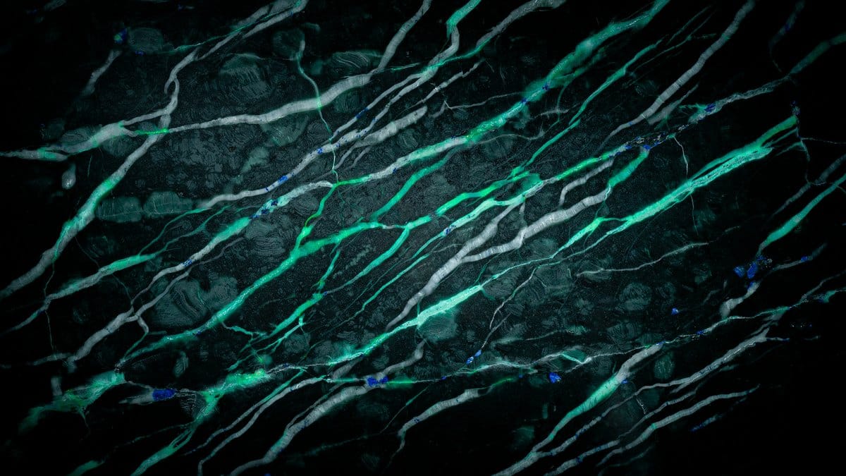 Black galaxy slab streaked with bright green and silver comet like veins