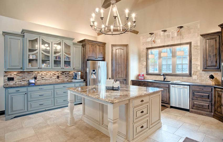 Green and brown kitchen cabinets with cream color island and travertine floors