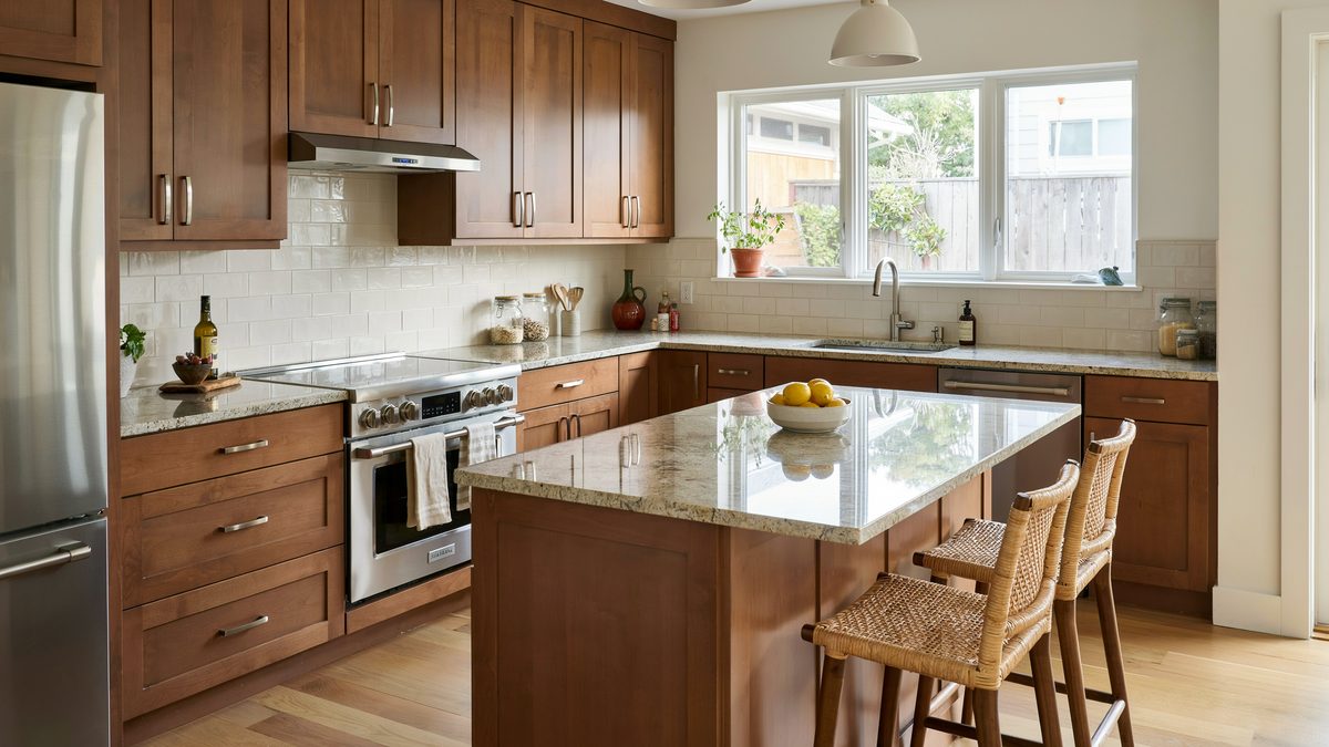 Medium walnut cabinets around an ivory gold island with rattan back stools