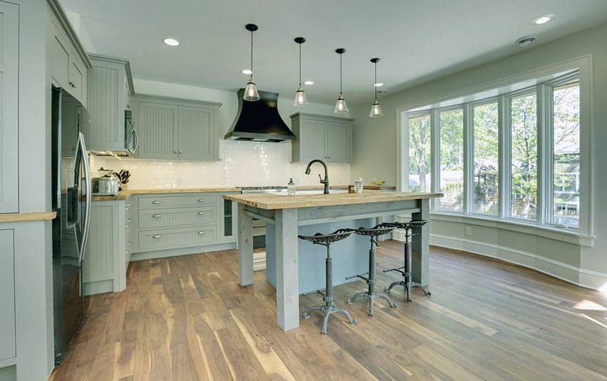 Light green kitchen cabinets with beadboard doors, bucherblock countertop island and wood flooring