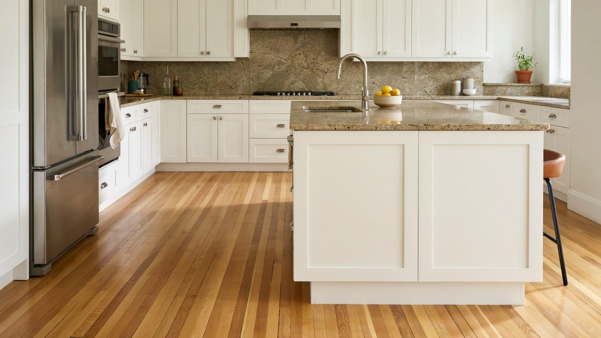 White inset cabinets paired with tan brown granite counters and honey oak plank flooring