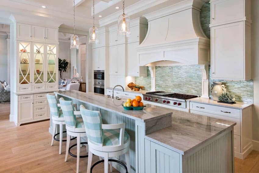L shaped kitchen with white shaker cabinets, gray island and glass mosaic backsplash