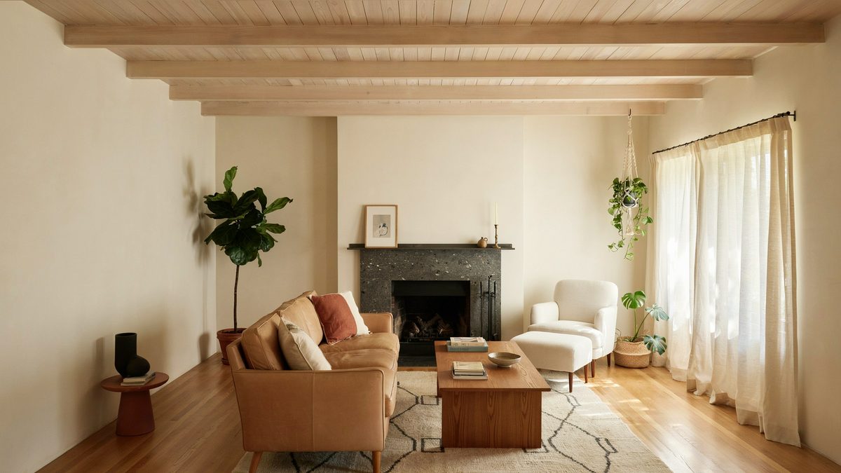 Room with faux wood beams, ottoman, fireplace and armchair