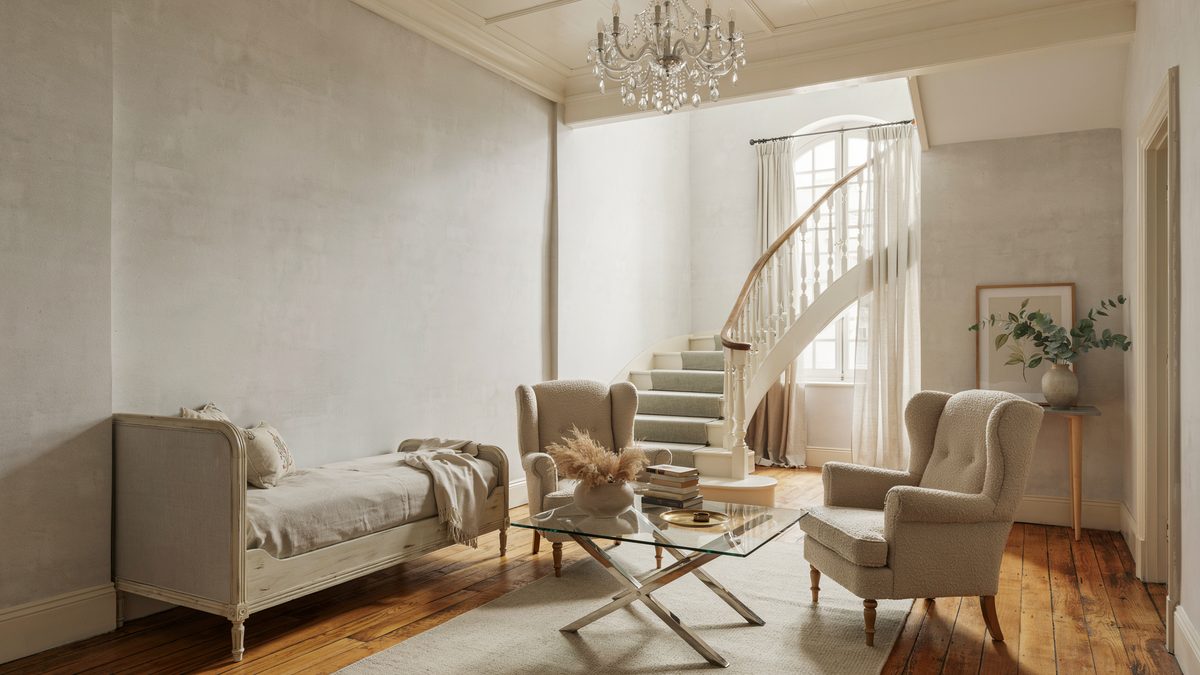 Room with gray French daybed, chandelier and stairs