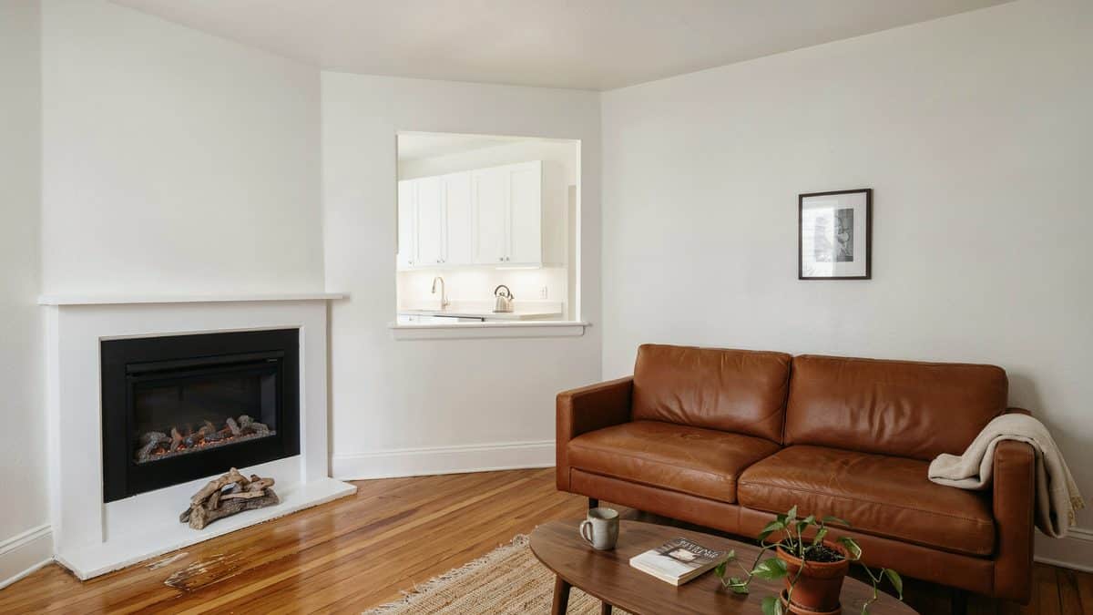 Room with open floor plan with weathered wood for the flooring and white kitchen cabinets