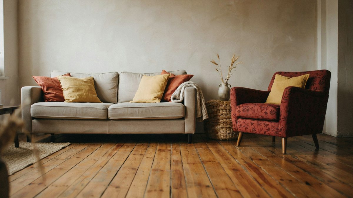 Beige sofa with brown piping accent, yellow throw pillows and wicker table