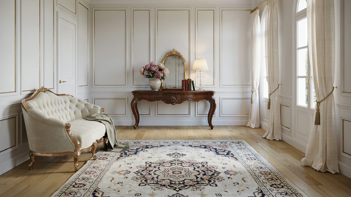 White paneled room with tufted chaise lounge and carved wood console table