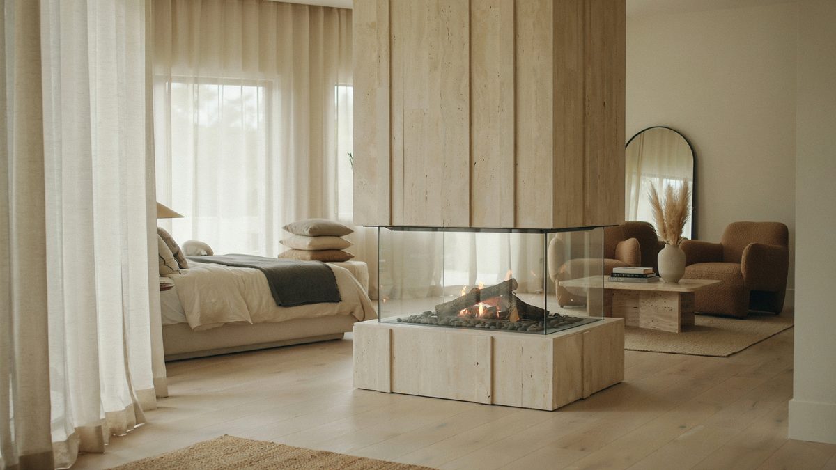 Freestanding travertine hearth glazed on three sides splitting the bed from a lounge