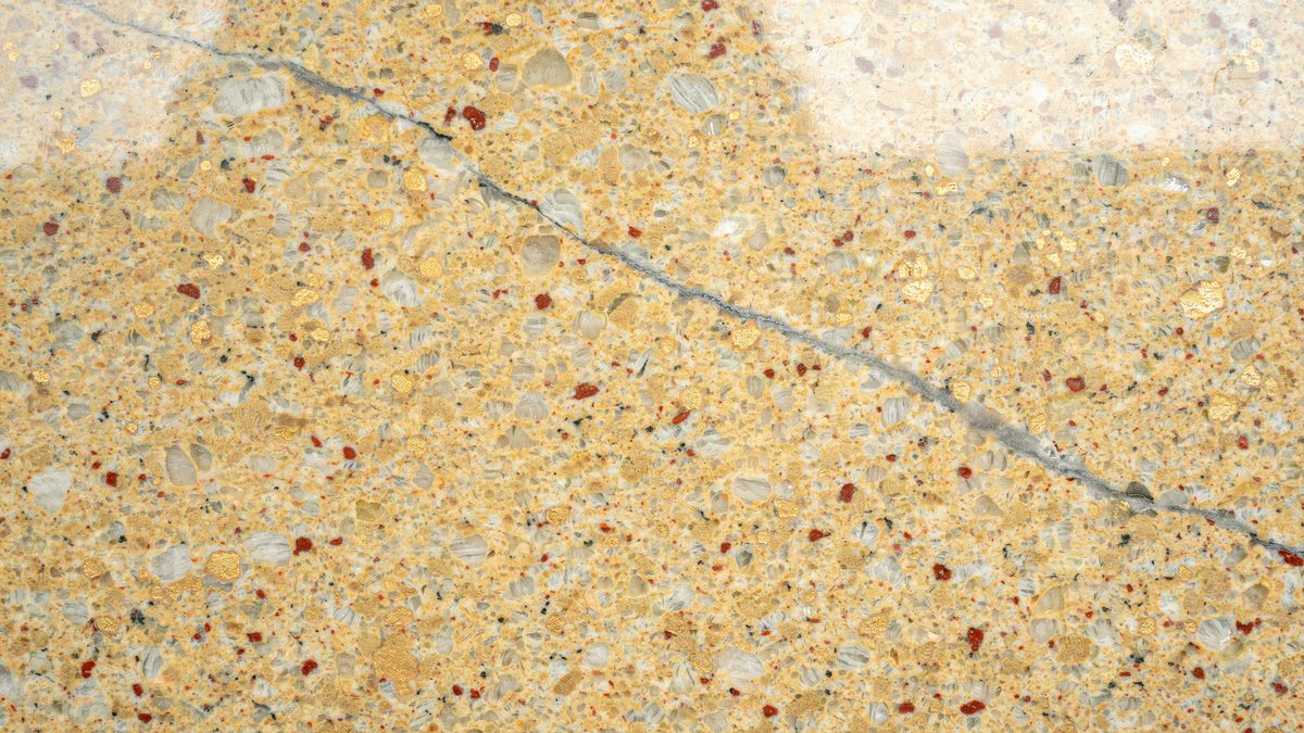 Sandy gold background peppered with red garnet flecks and a faint gray seam