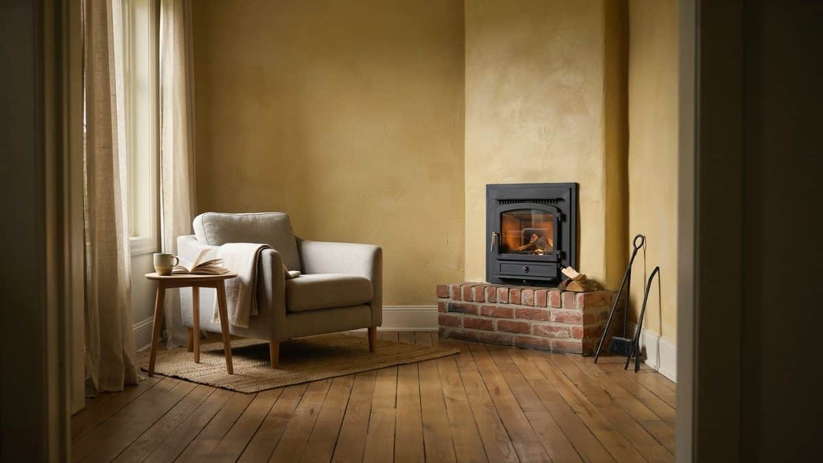 Black wood stove on a brick base tucked against warm ochre textured walls