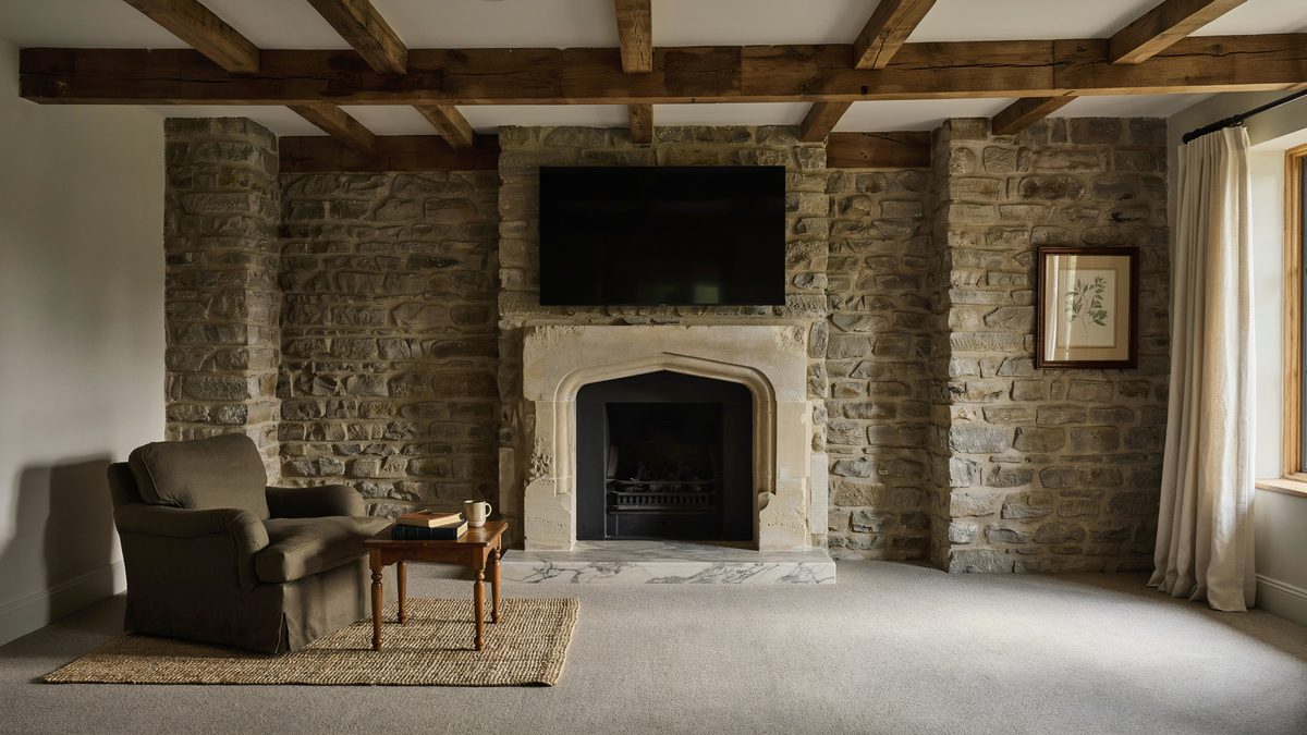 Gothic arched stone surround topped by a mounted TV between rough limestone walls