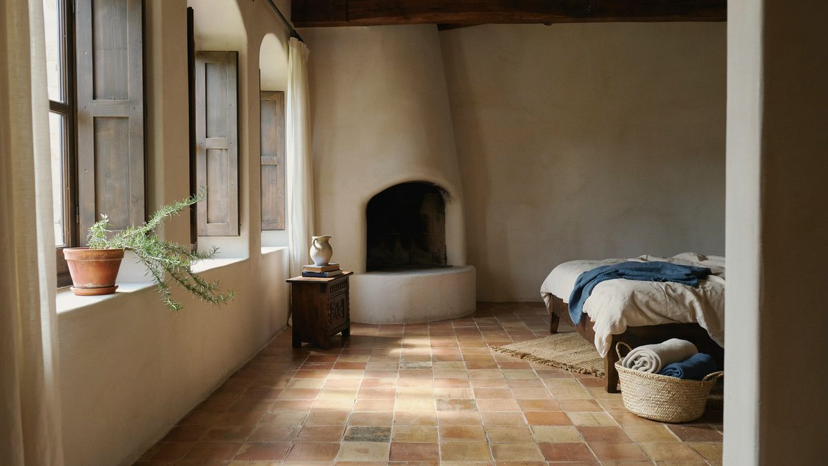 Rounded adobe corner fireplace with an arched opening above terracotta floor tiles