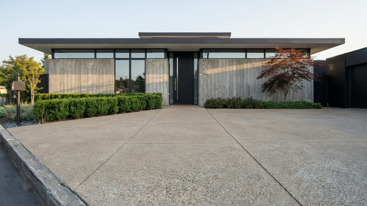 Broad aggregate concrete apron in front of a flat roofed mid century style home