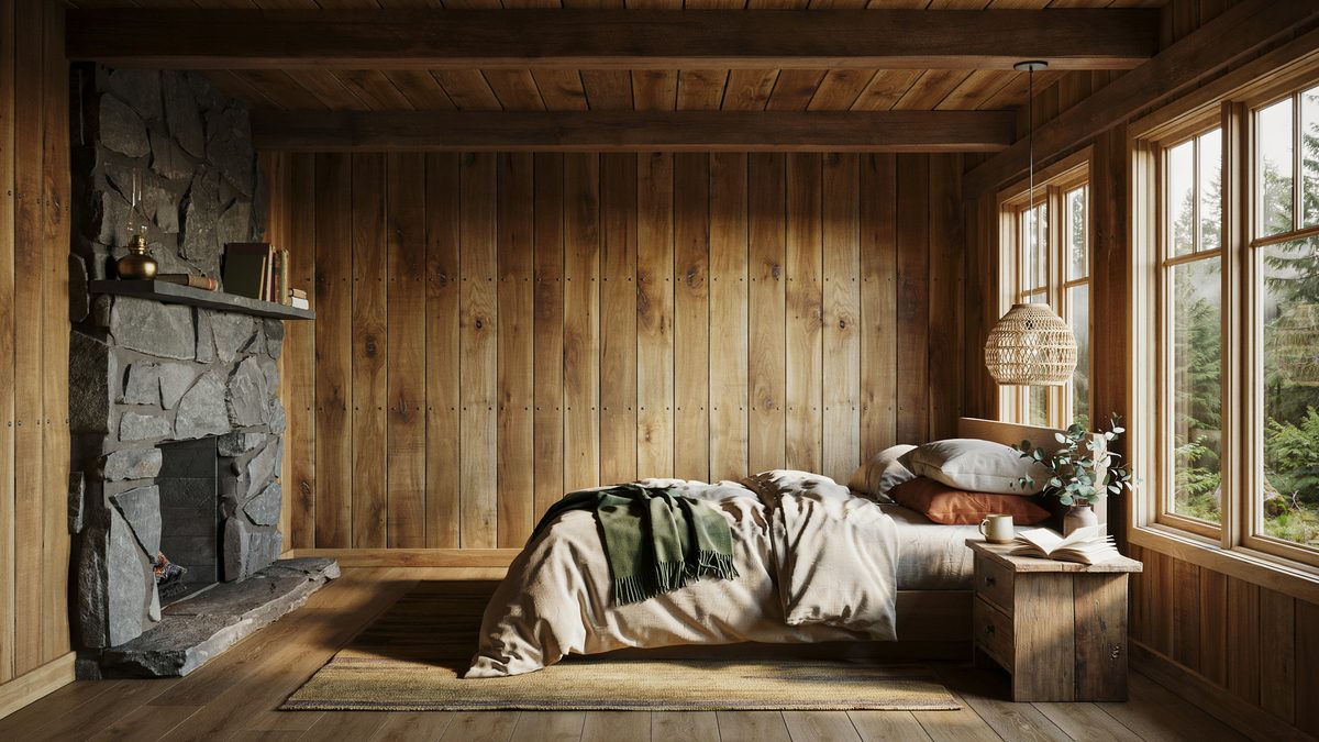 Rough fieldstone chimney against knotty plank walls with forest framed windows