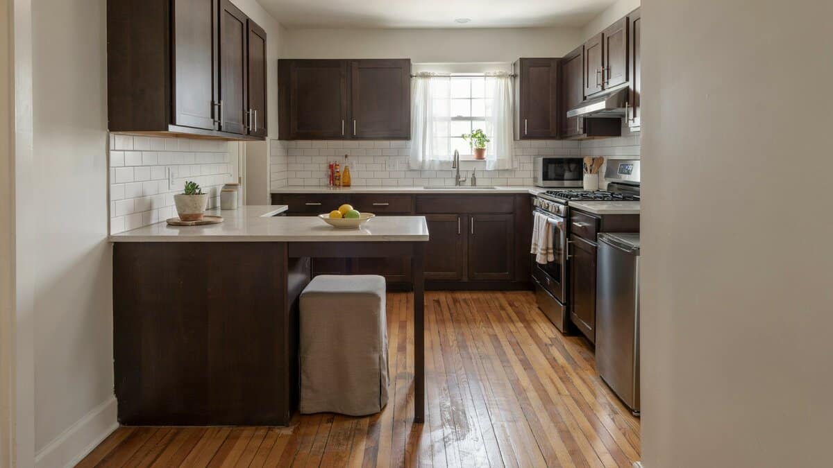 Narrow one person dining ledge extending from raised panel cabinets by the window
