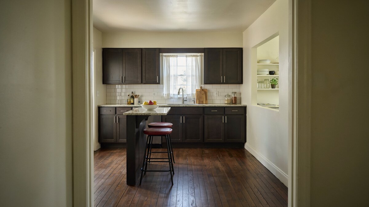 Red seated stools tucked under light granite against cream painted walls