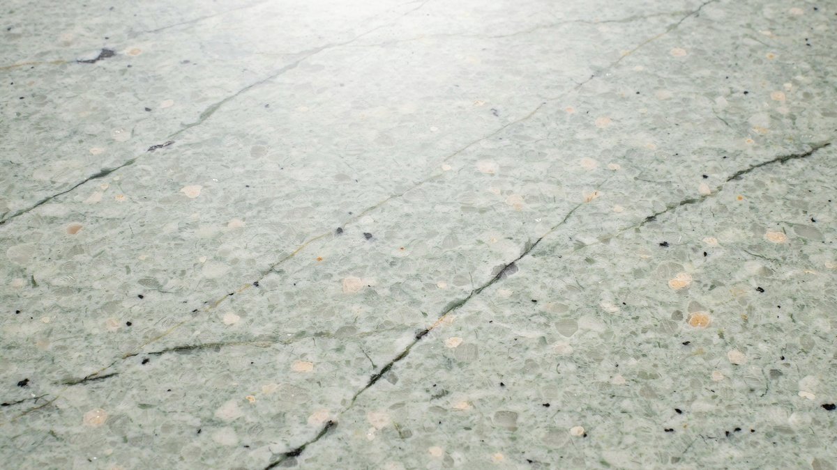 Pale gray green surf slab with faint hairline veins and beige speckles