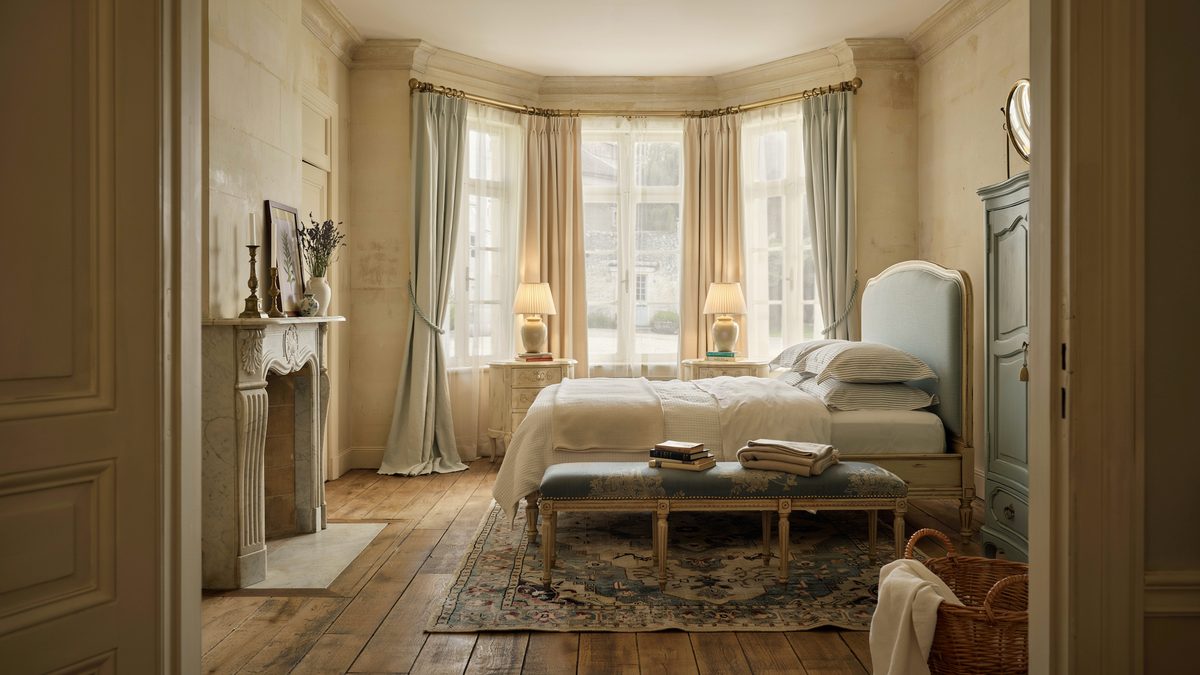 Bay window bedroom with stone fireplace, wood bench and pale blue armoire
