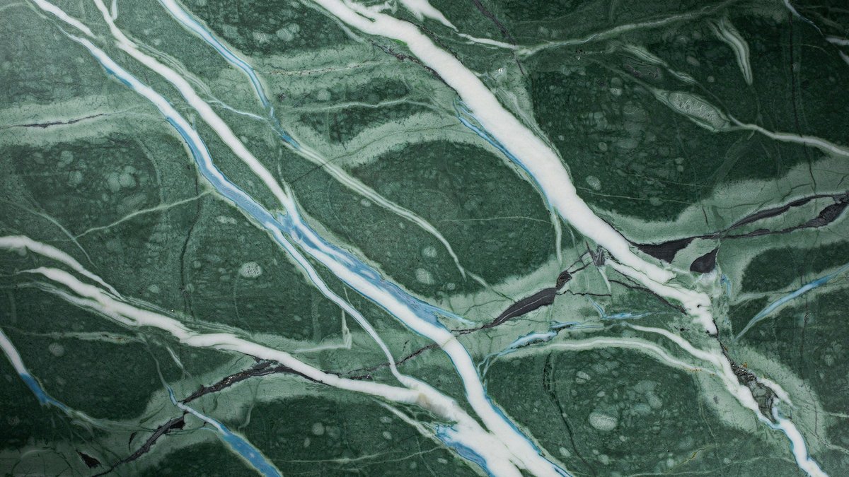 Deep green Kerala slab crossed by white and pale blue wave veins