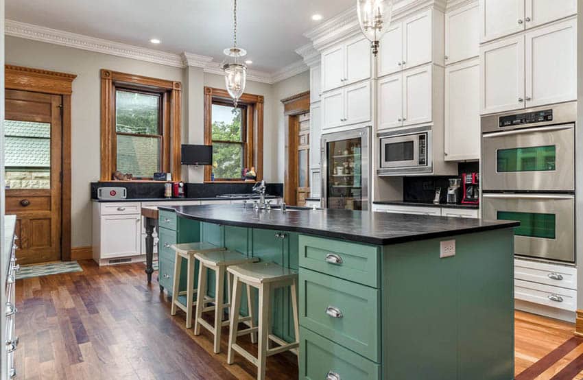 Green kitchen island with white cabinets and wood flooring