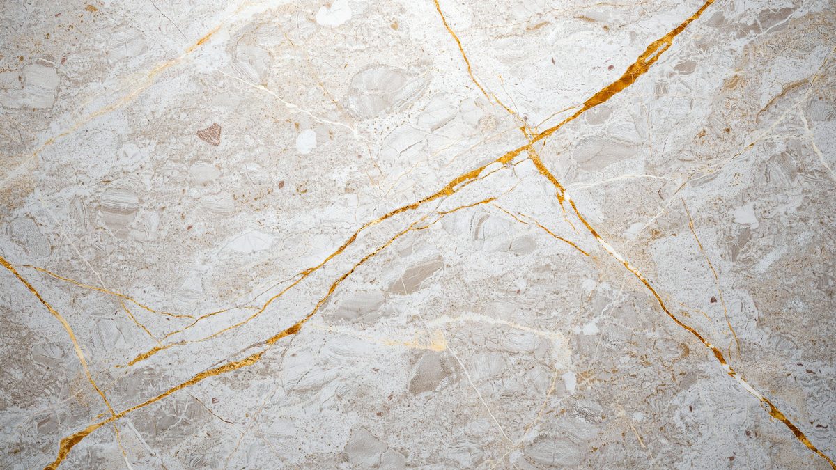 Pale gray and cream stone slab crossed by bold ochre gold veining