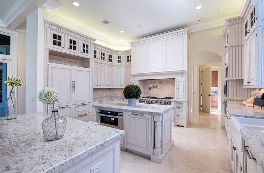 Antique white kitchen cabinets with beadboard, glass doors and column island with white granite countertops