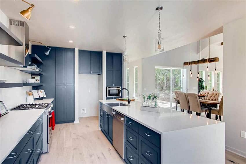 Contemporary blue cabinets in kitchen with white quartz waterfall countertops