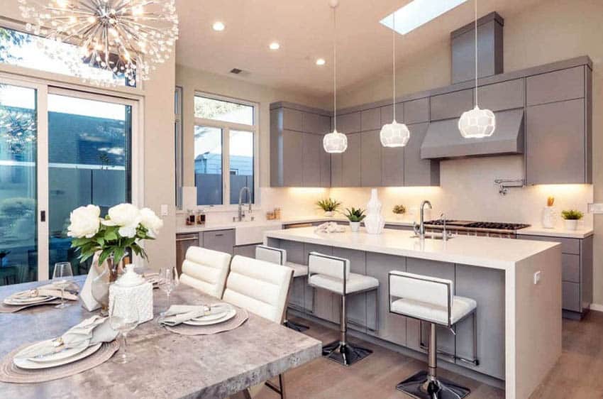 Contemporary crafted kitchen with eat in island, gray painted cabinets and quartz waterfall counters