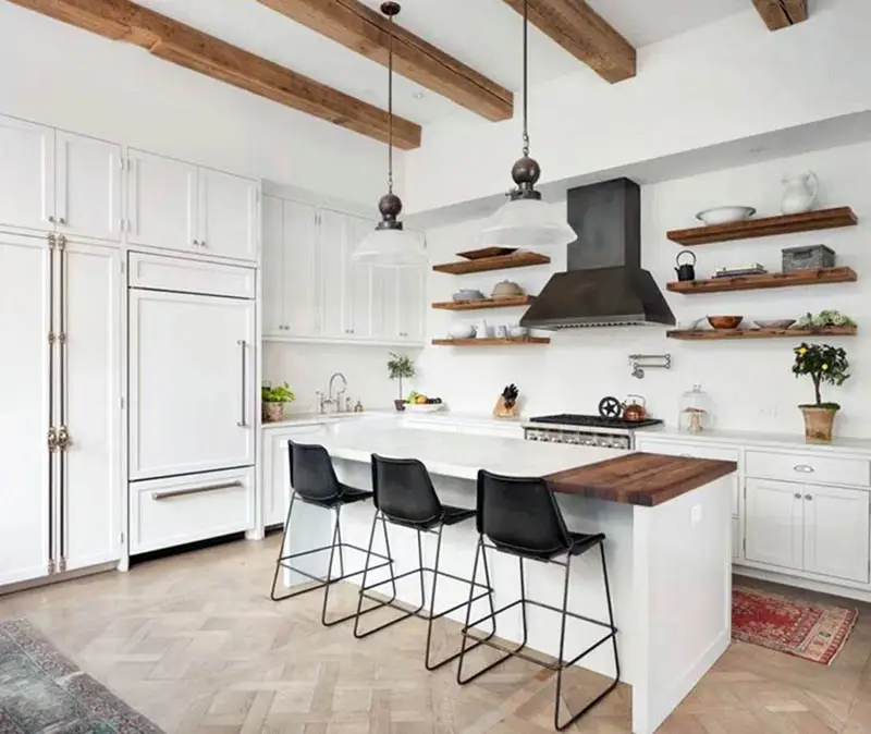 Country style kitchen with l shape and island with butcher block open shelving and wood beams